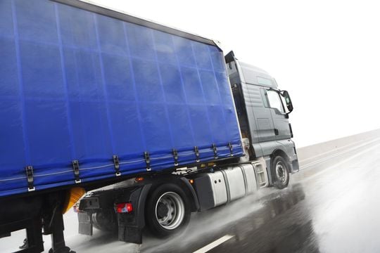 Blue lorry driving on wet road